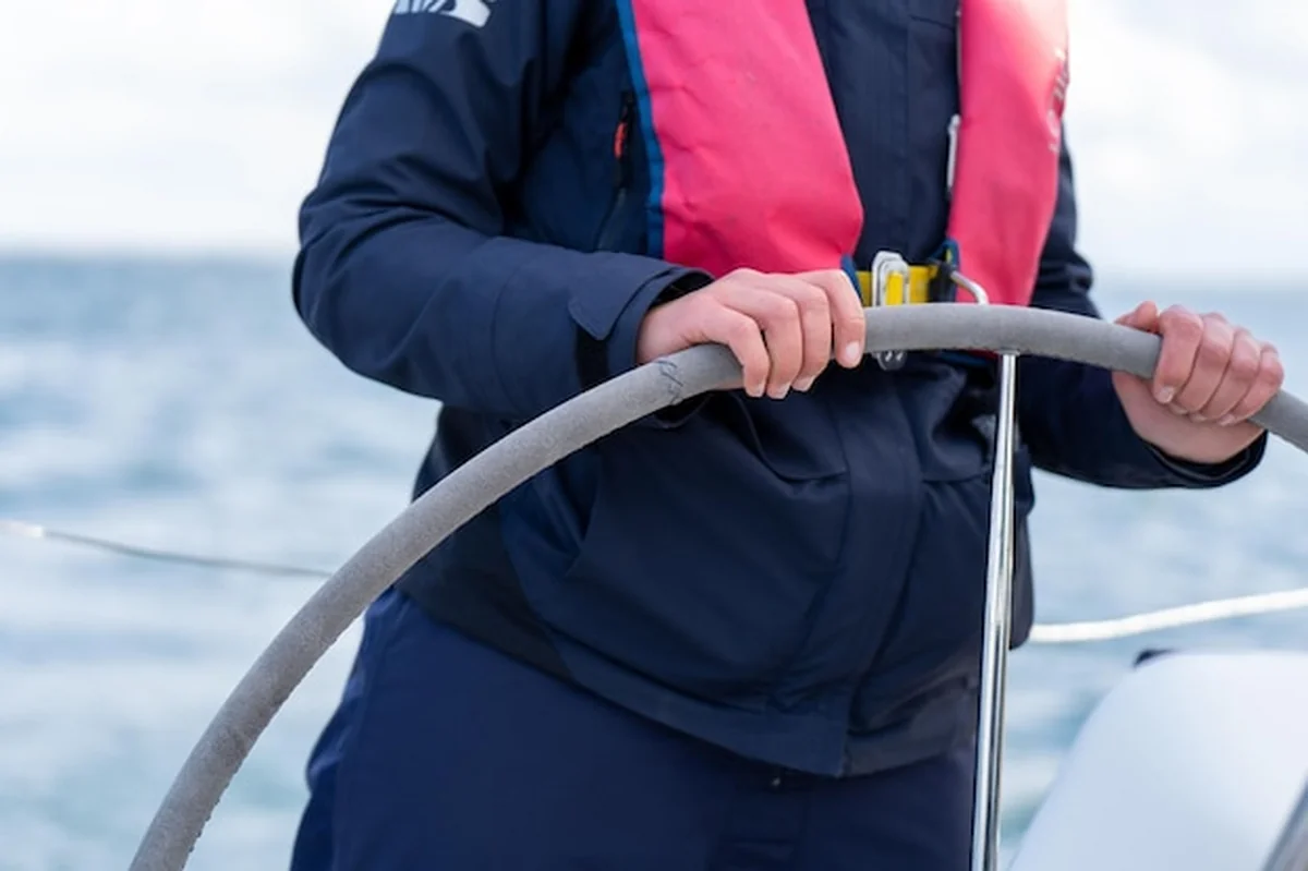 Osoba trzymająca koło jachtu w kamizelce ratunkowej