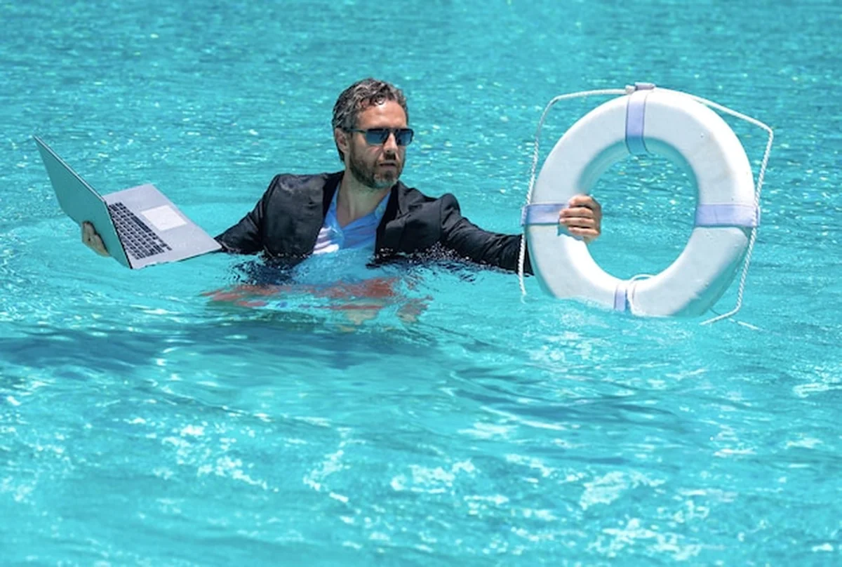 Biznesmen z laptopem i ratownik przy basenie