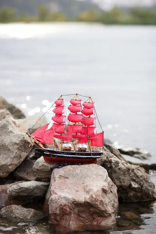 Statek ze szkarłatnymi żaglami na wodzie pod porannym niebem