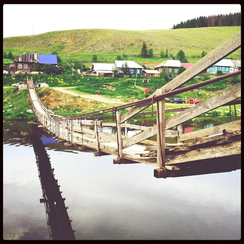 Most nad spokojnym jeziorem w tle domów