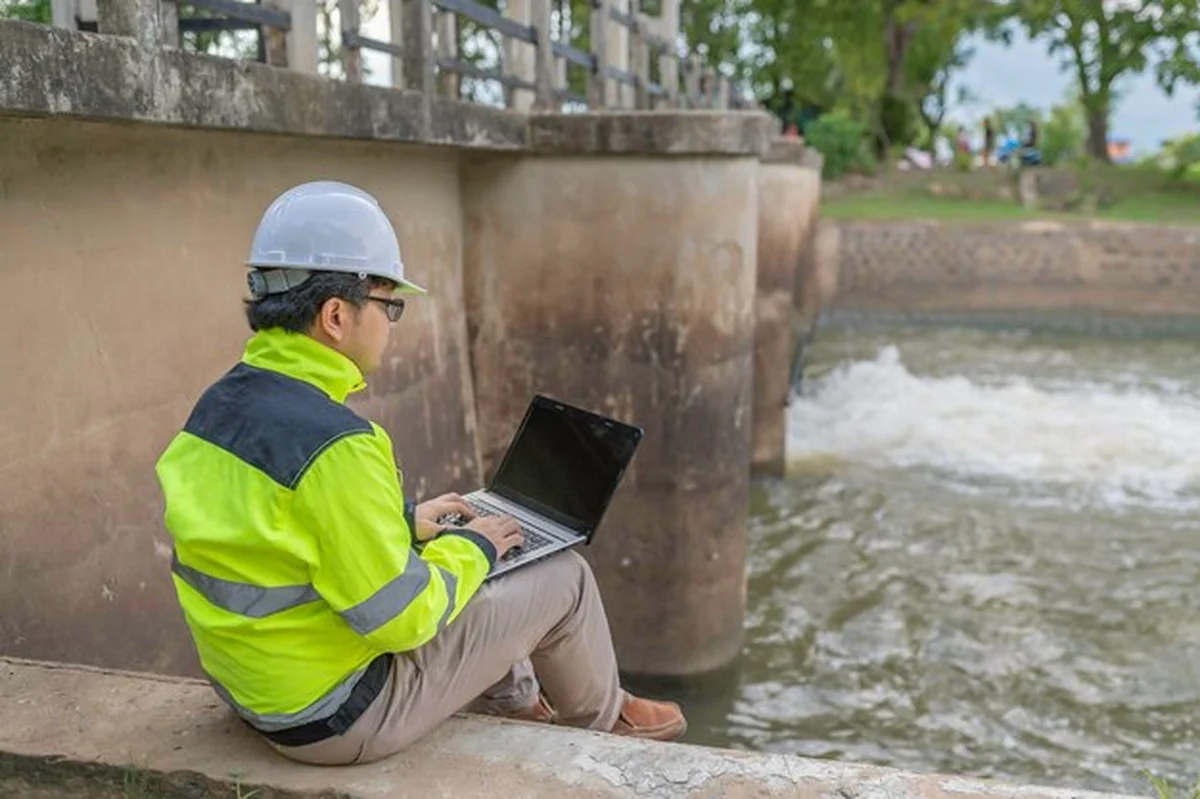 Inżynier monitoruje poziom wody przy tamie podczas ulewnego deszczu
