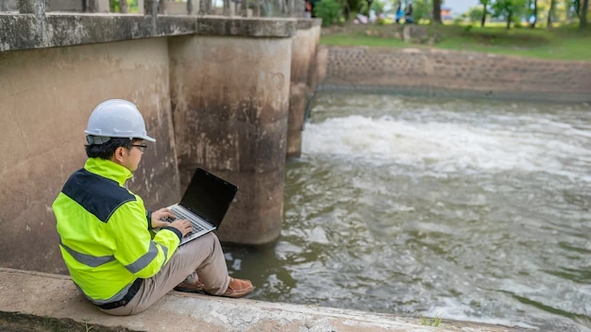 Inżynier kontroluje poziom wody przy tamie w kasku i mundurze inżyniera podczas ulewnego deszczu